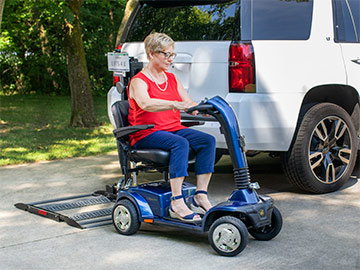 Woman on mobility scooter in front of Bruno Out-Sider and SUV